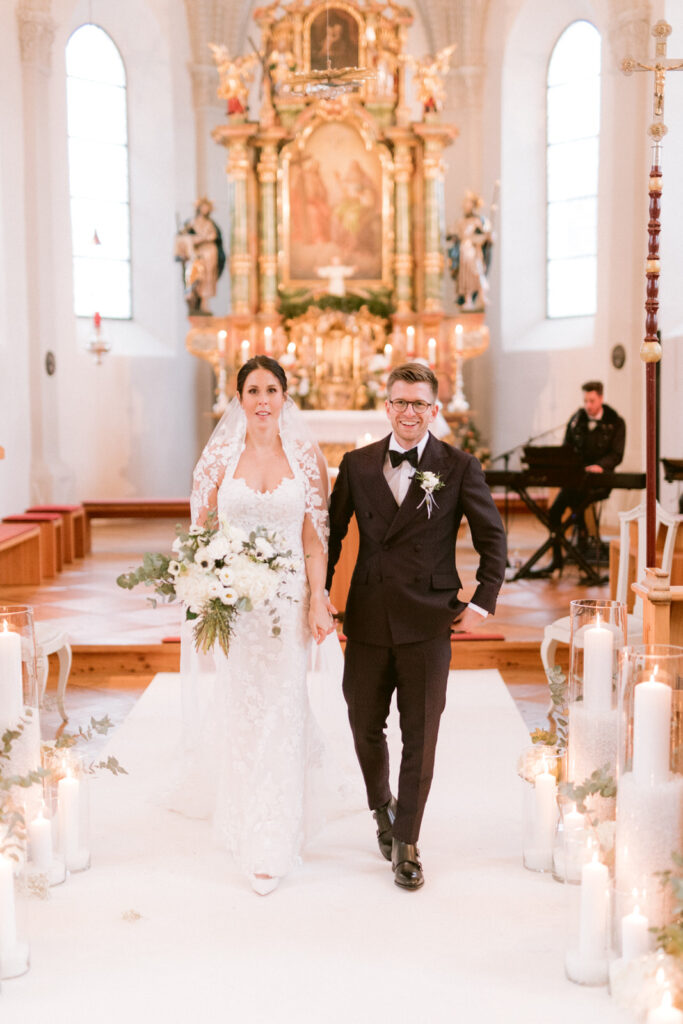 Bridal couple walking on the aisle of the church at a winter wedding; Alpine-Wedding-Planner